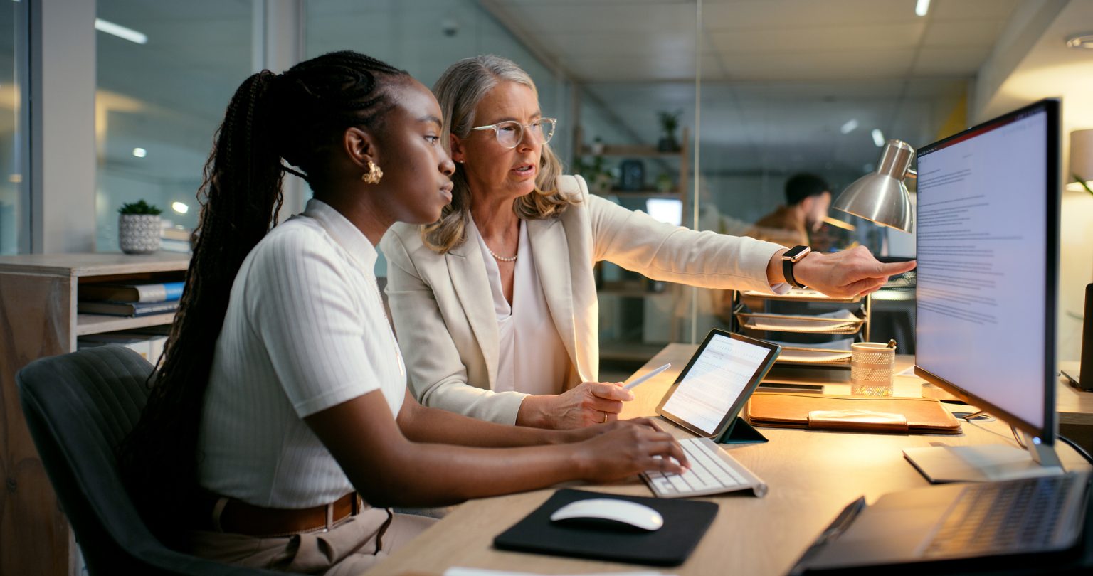 A mentor guiding a trainee through material at a desk