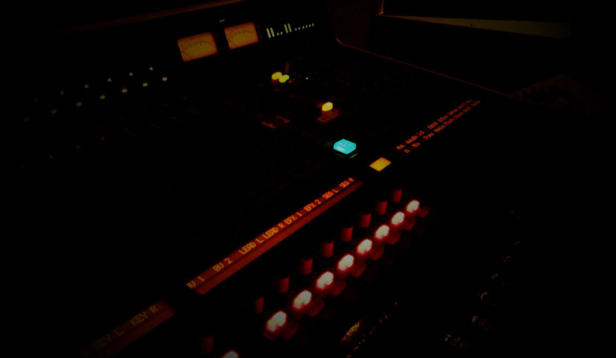 Close-up of an illuminated radio studio mixing desk in low light