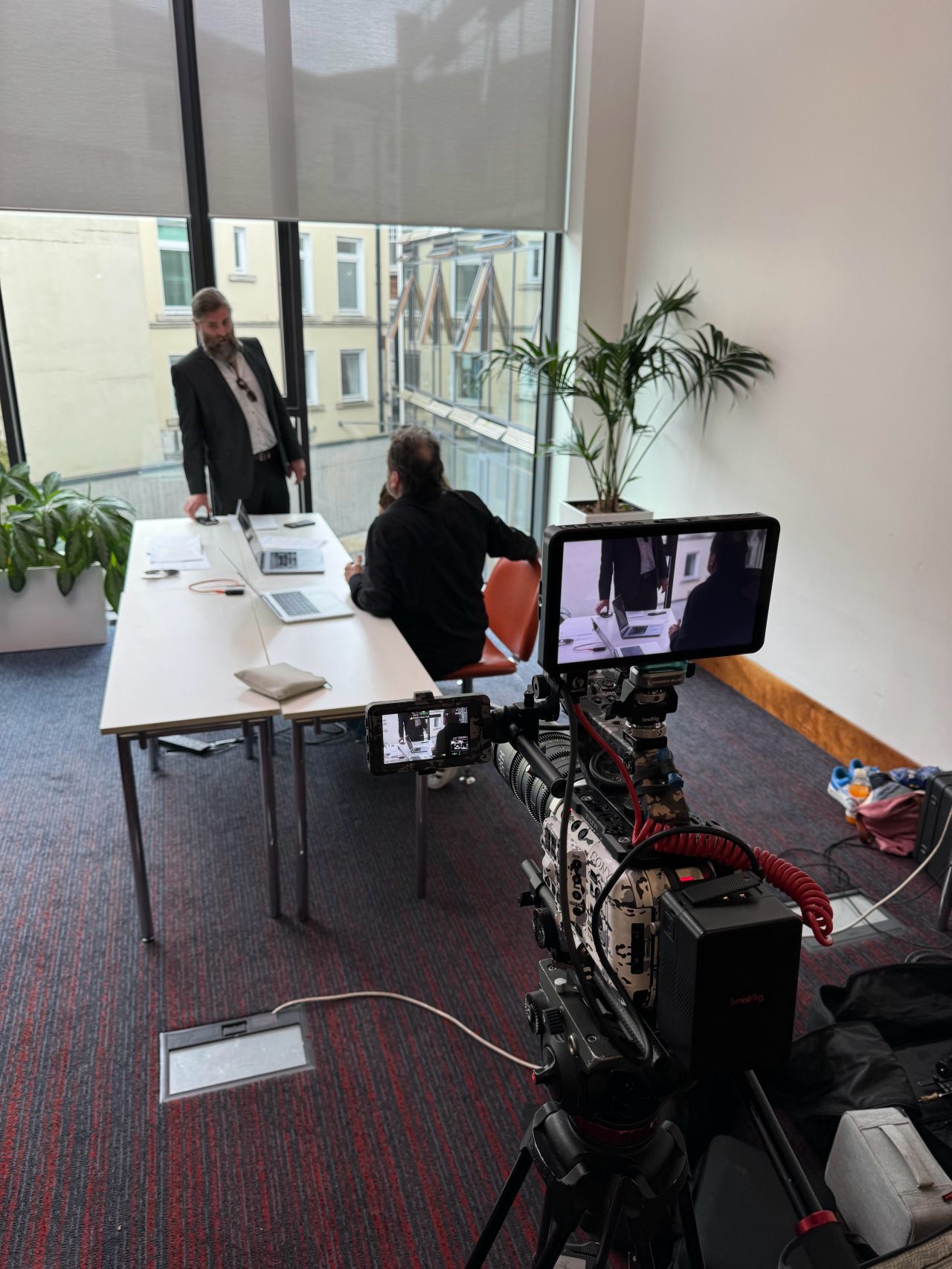 Filming a Be the Boss scene in an office meeting room, with the camera monitor in the foreground