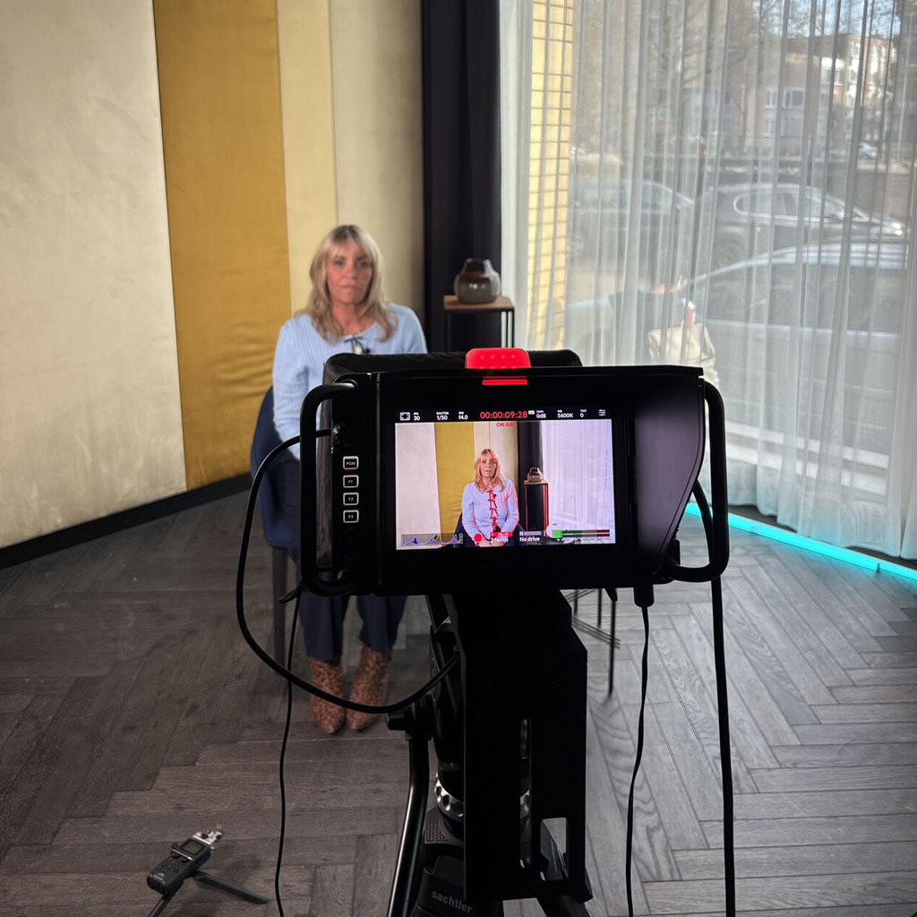 Interviewee seated in front of the camera, with the shot on the monitor, during filming in Amsterdam