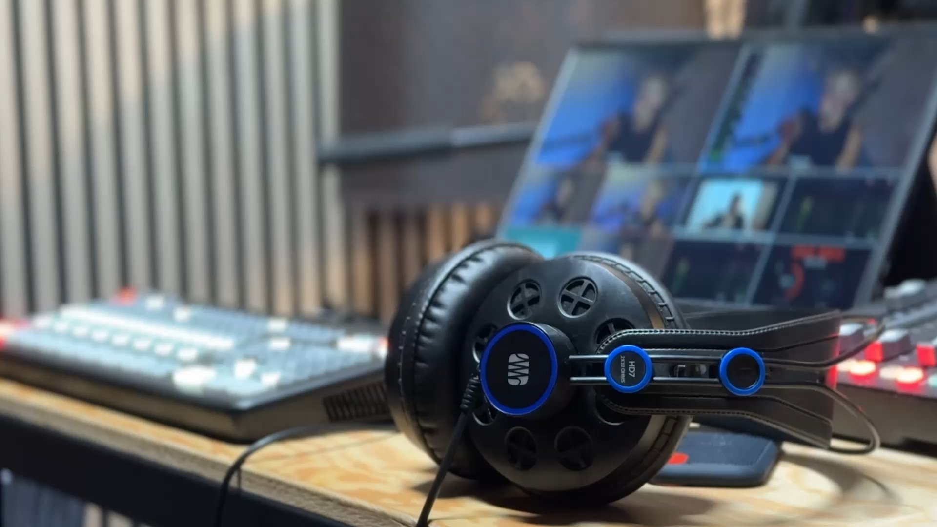 Headphones on the desk of Big Top’s studio control room, vision-mixer screens behind